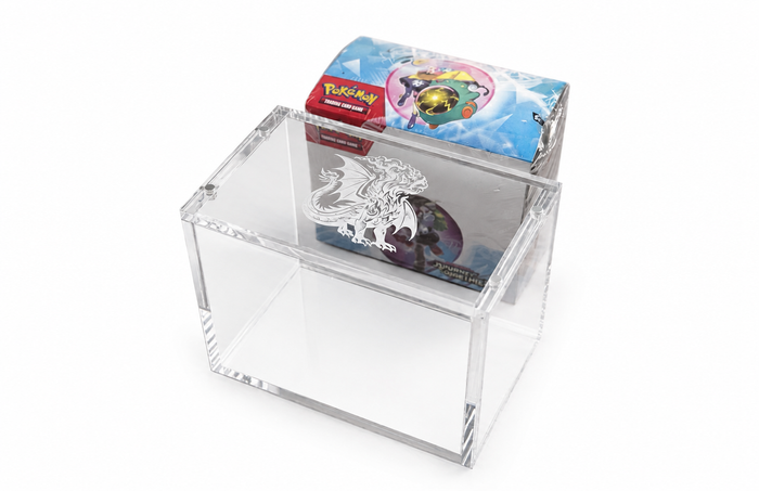 Pokémon TCG-boosterboks ved siden av akrylboksen på hvit bakgrunn